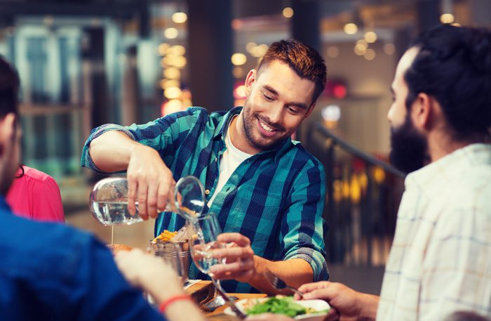 How to Turn Down Alcohol in Social Settings - guy pouring water at dinner with friends