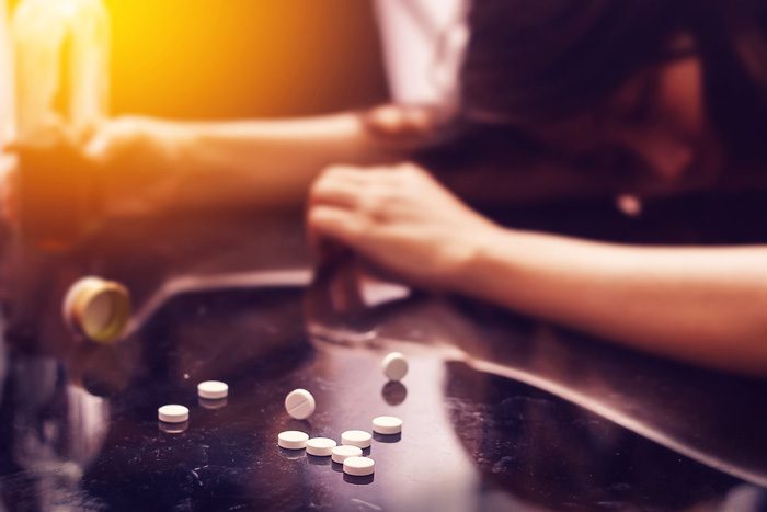 Dangers-of-Drug-Mixing-Opioids-and-Alcohol - girl passed out at table or bar with alcohol and spilled pills