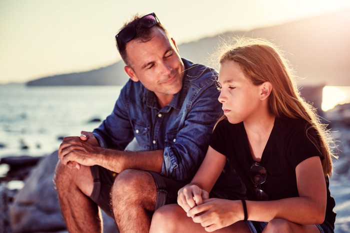 handsome father talking to teenage daughter on beach - drug test