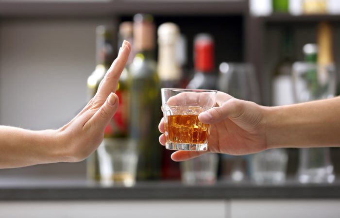 closeup - person offering glass of liquor - other person with stop hand gesture - alcohol