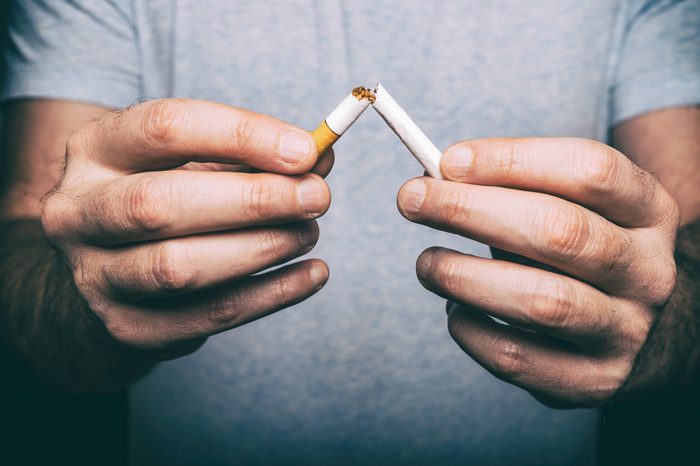 closeup of man breaking cigarette in half - quit smoking